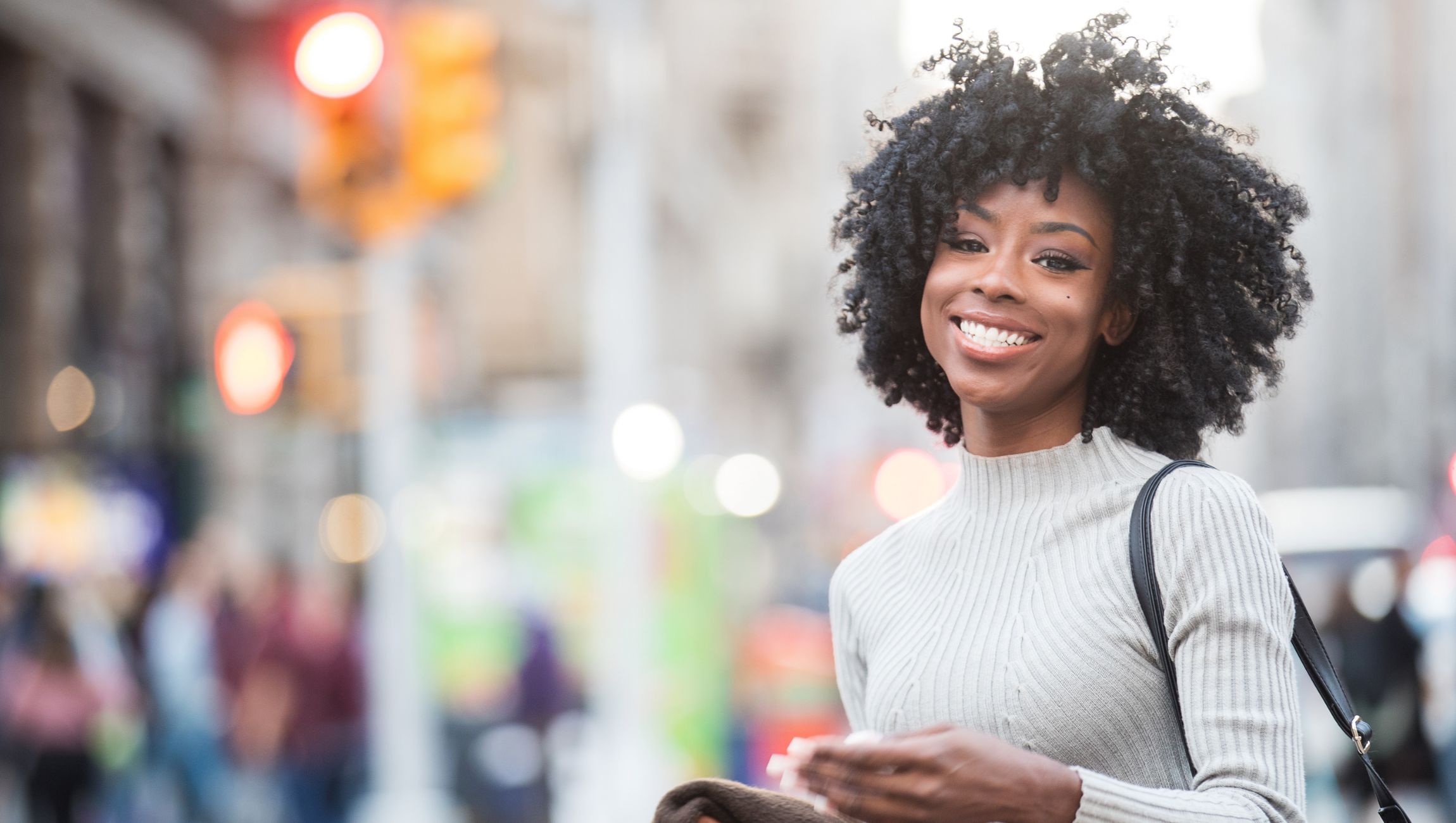young woman with naturally curly hair outside in a city