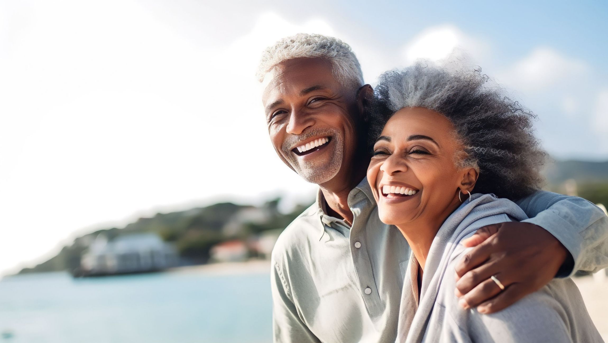 an elderly couple at the edge of a body of water smiling