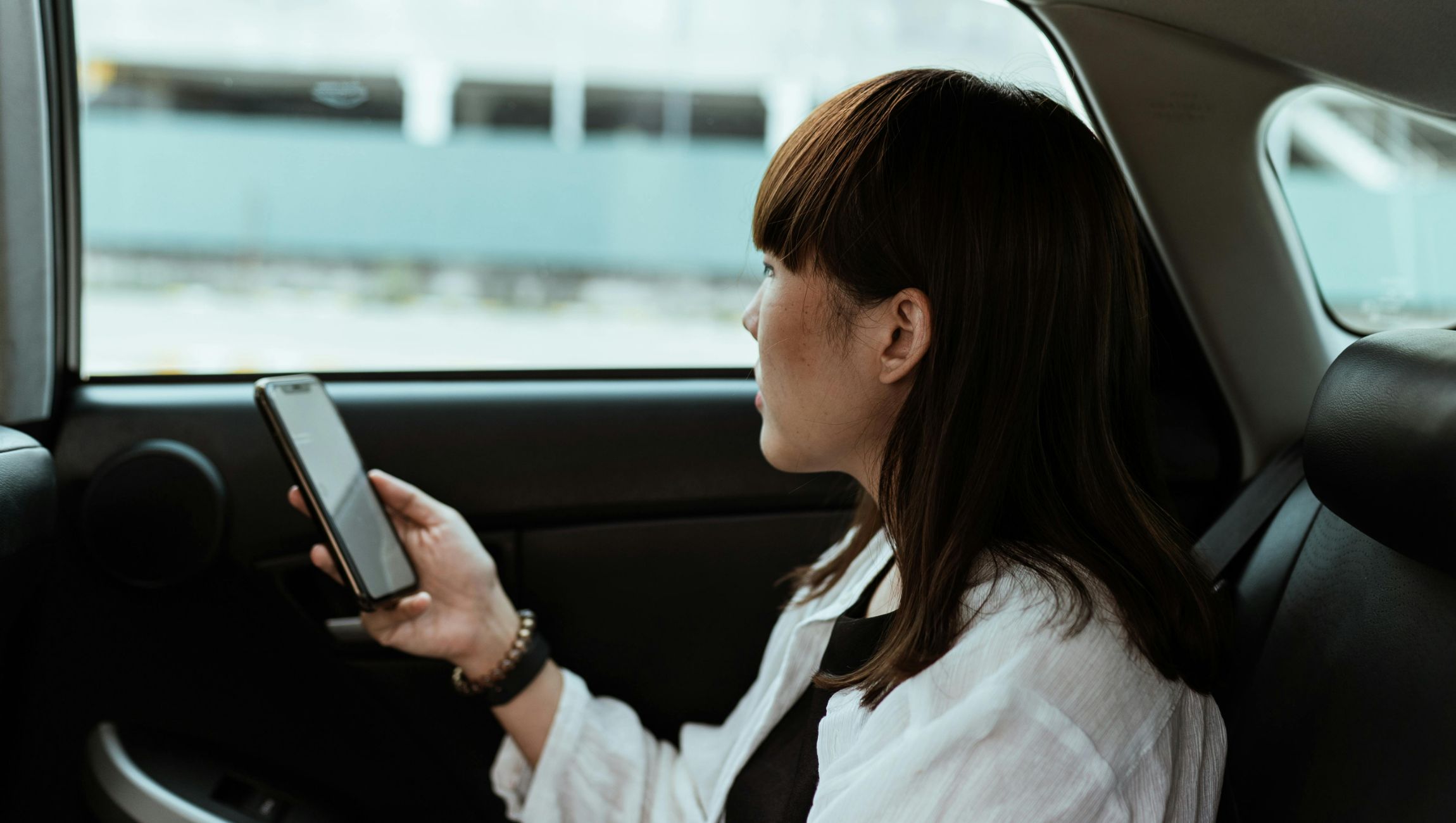 a woman in the back seat of a car on her phone
